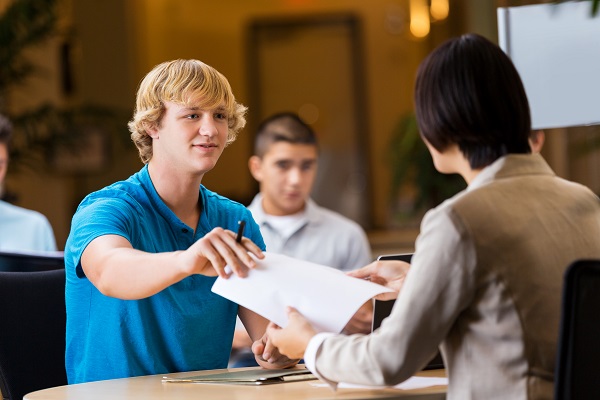 Young man handing paper to potential employer